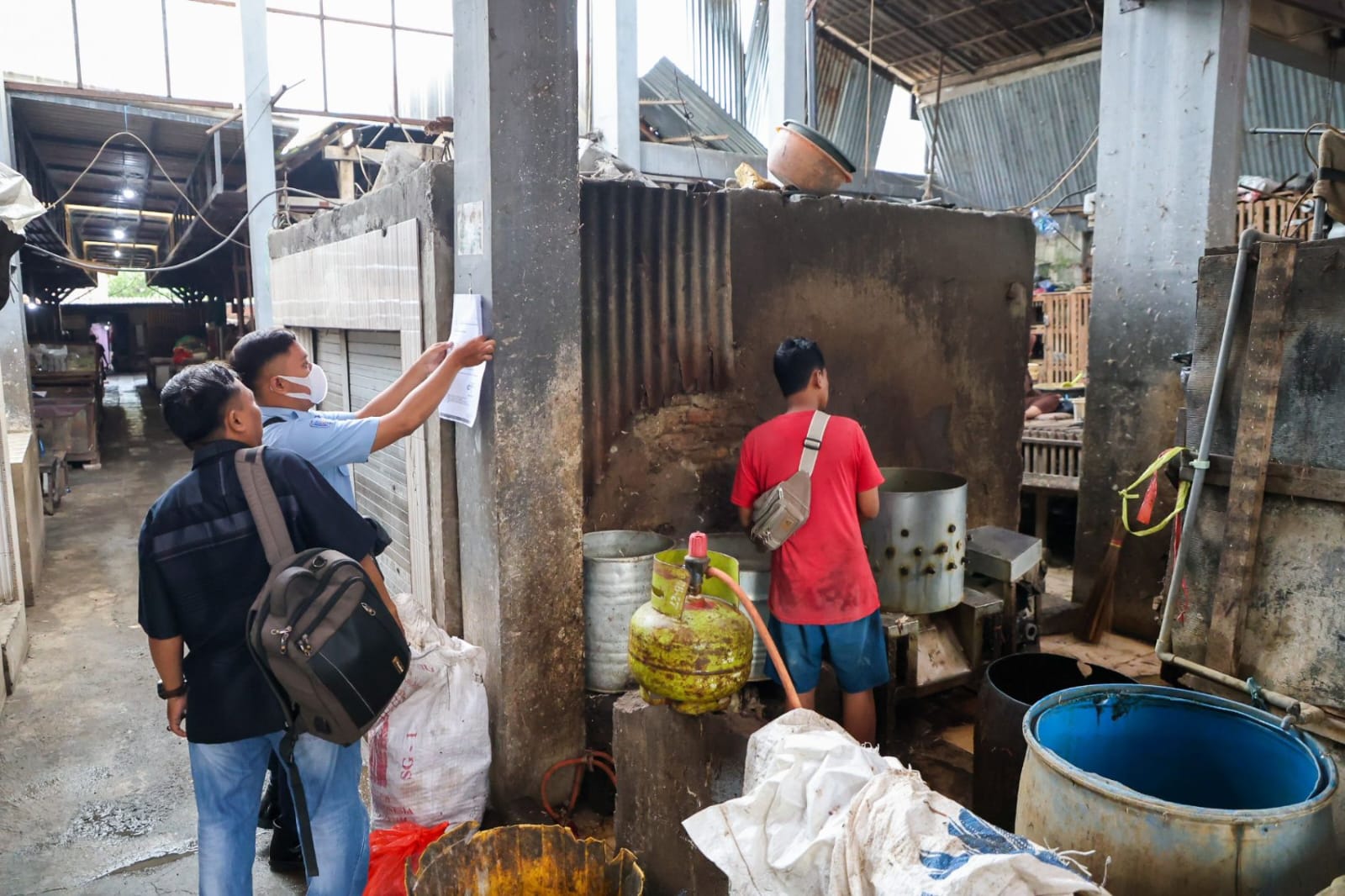 Petugas menempelkan lembar sosialisasi di beberapa titik di Pasar Tembok Dukuh, Bubutan, Surabaya (Dok. Humas Pemkot Surabaya)